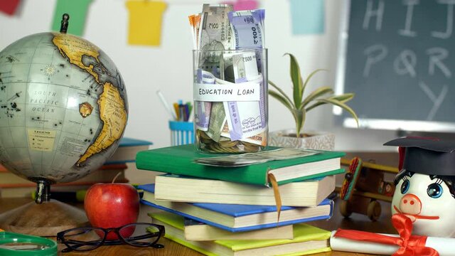Indian woman's hand donating money in a glass jar with "educational loan" label. Closeup shot of a female's hand saving banknotes in a jar to pay her education loan - education/finance concept