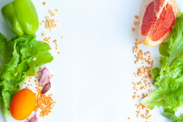 Background healthy vegan food lettuce, grapefruit, sweet pepper, garlic, yellow tomato, red lentils and dry peas, flat lay, copy space
