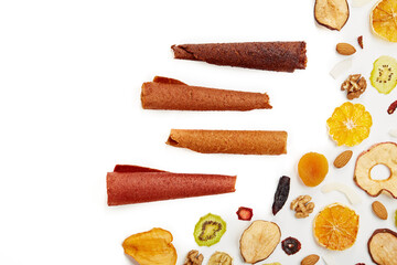 Above view of tasty lozenge with fruits and berries at table and dried fruits kiwi, orange, apple, apricot and bananas on white background. Concept of healthy assorted dried fruit for snacks.