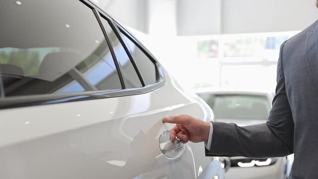 Close up adult man customer male buyer businessman client wears classic suit chooses auto wants to buy new automobile in car showroom vehicle salon dealership store motor show indoors. Sales concept
