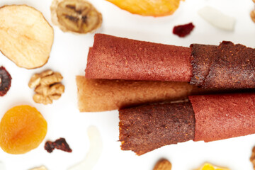 Above view of natural fruit and berries lozenge different colors and dried fruits bananas, apricot and nuts on white background. Concept of natural sweets from tasty berries and for healthy snacks. 