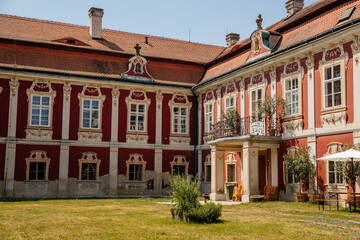Obraz premium Baroque castle Steknik, stucco, peeling dark red plaster, red tile roof, green lawn, italian garden, aristocratic residence in summer sunny day, ancient chateau Steknik, Czech Republic