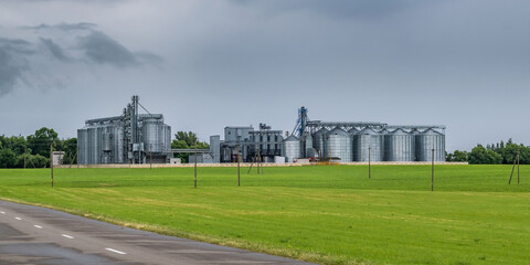 Fototapeta na wymiar Modern Granary elevator and seed cleaning line. Silver silos on agro-processing and manufacturing plant for processing drying cleaning and storage of agricultural products, flour, cereals and grain.