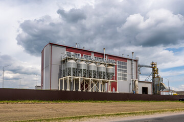 Modern Granary elevator and seed cleaning line. Silver silos on agro-processing and manufacturing plant for processing drying cleaning and storage of agricultural products, flour, cereals and grain.