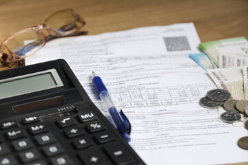 On the table is a receipt for payment, a pen, glasses, money, and a calculator for counting money....