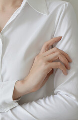 Close up look of woman wearing white blouse and crossing her arm 