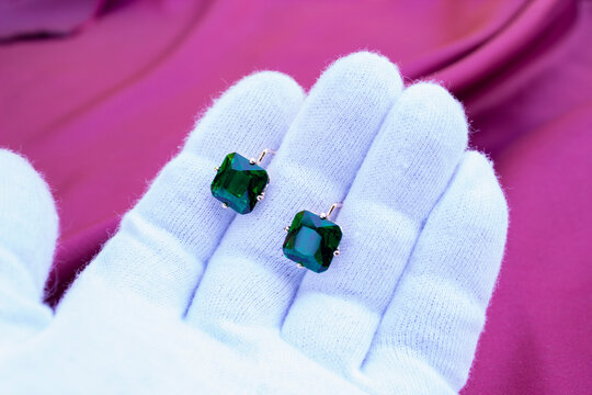 hand in white glove holds aquamarine crystal on white background