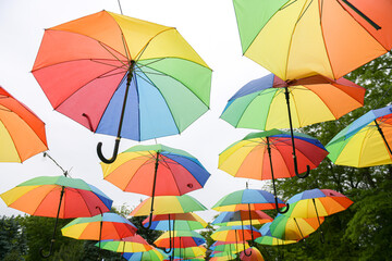 Fototapeta na wymiar A lot of umbrellas hanged in a park. Beautiful view with a lot of color. Vivid photo.