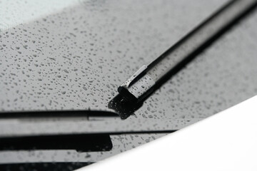 Automotive industry. Close up view of a pair of car wiper blades with small raindrops on window.