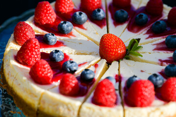Close up view of a delicious cheesecake ready to be served as a desert with forest fruits on top of it.