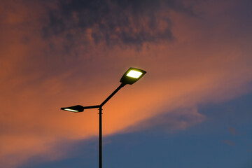 Public street lighting pole with LED lights with an amazing sunset color background. - obrazy, fototapety, plakaty