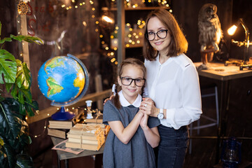 A good kind Teacher teaches a student. Mother hug her daughter. Studying geography in elementary school. Science classroom. Support from a friendly tutor. Back to school concept