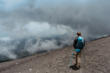 Backpacker hiking to Etna,Sicily,Italy.Adventure outdoor activity.Excursion on summit of volcano.Parco dell'Etna,protected nature area.Travel freedom background.Hiking man on summer vacation.