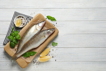 Fresh raw pike perches and ingredients on white wooden table, flat lay with space for text. River...