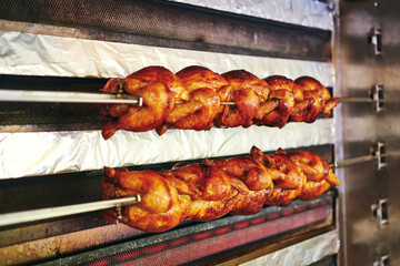 Grill Hänchen auf Stangen im großen Hänchengrill schön knusprig gegrillt im Biergarten  