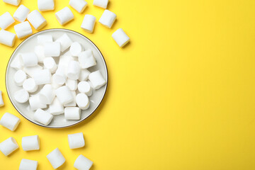 Delicious puffy marshmallows on yellow background, flat lay. Space for text
