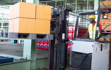 Professional African America worker using forklift machine in storehouse.