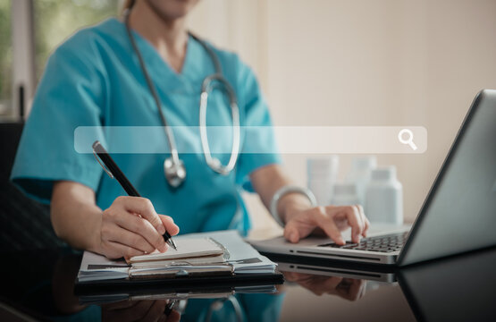 Doctor working with a laptop search and take notes for medical information at the hospital office during the day.