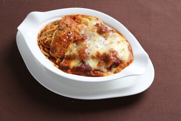 oven baked creamy cheese tomato Bolognese pasta with grilled chicken chop in bowl western chef cuisine seafood menu in white and brown background