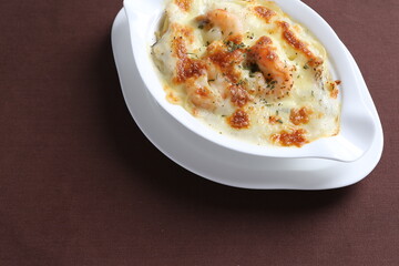 oven baked creamy cheese carbonara pasta with fresh big prawn in bowl western chef cuisine seafood menu in white and brown background