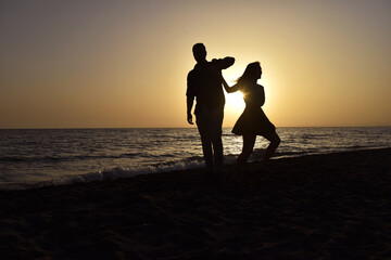 Fototapeta premium Couple on the Beach Dancing at Sunset