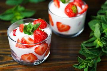 Whipped cream and strawberries served in a glass. Dark wooden table, high resolution
