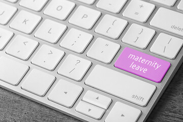 Modern computer keyboard with text MATERNITY LEAVE on table, closeup