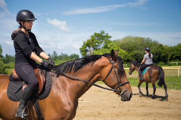 Training in the riding school, two girl riders and sorrel horses