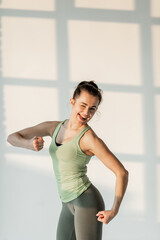 Fototapeta na wymiar Portrait of a cheerful athletic woman in green sportswear during fitness training