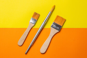 brushes and roller to paint on smooth orange and yellow background