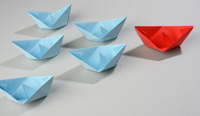 group of paper boats on a gray background. concept of a strong leader in a team, manipulation of the masses