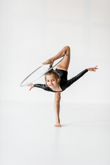 Little girl practising rhythmic gymnastic with a ring at white room. Children's gymnastics and training from an early age