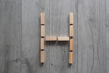 letter H natural wooden blocks on floor alphabet lettering