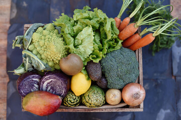 Flat lay of a basket of organic vegetables on a slate background