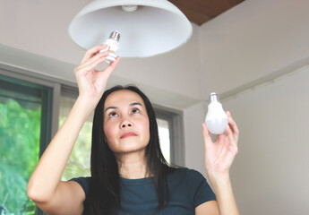 woman  changing light bulb , from spiral  light bulb to LED light bulb. Slective focus on woman...