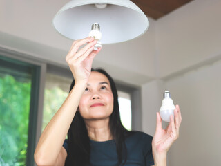 woman  changing light bulb , from spiral  light bulb to LED light bulb.