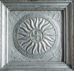 Swastika sign embossed on a silver metallic plaque. Decorative antique hindu religious motifs or symbols from temple.