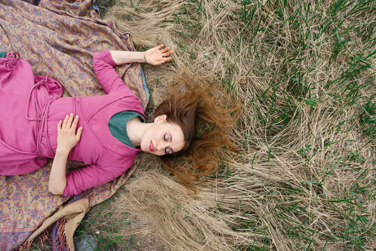Young beautiful  woman wearing dress lying on the grass. Meditation, unity with nature, relaxation