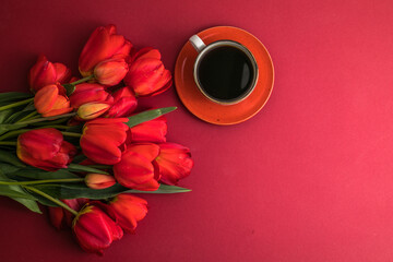 Bouquet of red  tulips and coffee cup arrangement with a lot of copy space for text. Spring mood concept. Greeting card for Birthday, Woman, Mother's Day, Wedding, Valentines day.