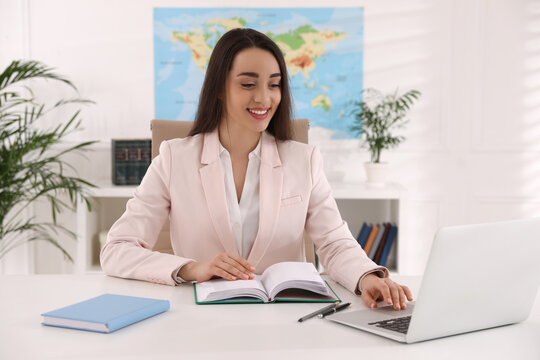 Happy Manager Working With Laptop At Desk In Travel Agency