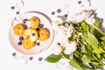 Profiteroles with blueberries. Custard cakes, Eclair, cream puff on a wooden stand