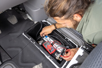 Man checking batterie inside the floor of a van