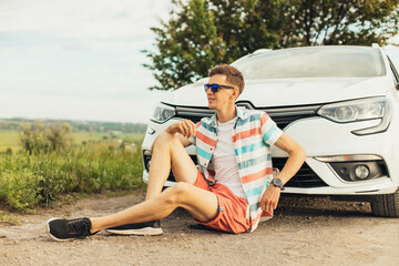 young handsome happy man in sunglasses, travels by car, rent a car on vacation, travel concept