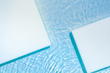 Two empty white square podium on transparent clear calm blue water texture with splashes and waves...