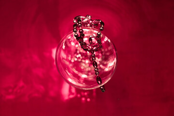 Abstract red background with glass vase and beads, reflection, shadow, sunlight, minimal natural luxury, copy space