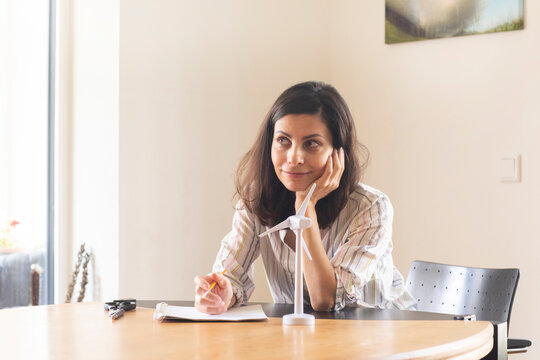 Germany, Freiburg, Female engineer sitting at table with model of wind turbine