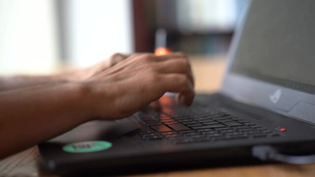 Homme qui tape sur le clavier de son ordinateur portable.