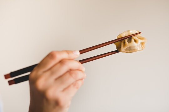 Hand of woman holding chopsticks with dumpling