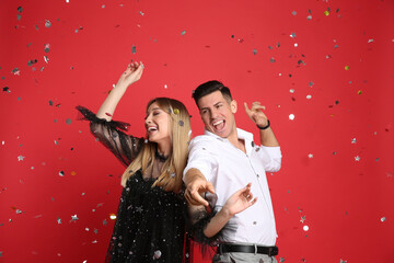 Happy couple and confetti on red background
