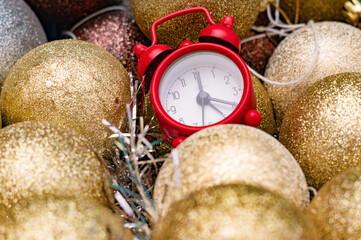 Tiny alarm clock in box with gold shiny Christmas toys. New year concept